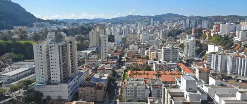 Vista panorâmica de Juiz de Fora, destacando a arquitetura urbana e os imóveis em Juiz de Fora, com prédios modernos e montanhas ao fundo, ideal para quem busca morar ou investir.